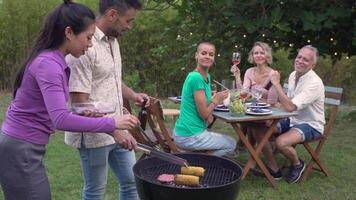 multiethnic middle-aged people around the barbecue smiling happy and laughing. Joy concept in slow motion video