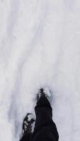 A first-person perspective of someone walking through fresh snow, with winter boots partially covered in snow. Footsteps mark the path, highlighting the cold winter environment video