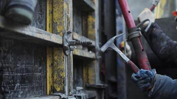 Worker adjusting formwork connection with hammer video