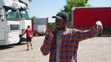 Truck supervisor walking at parking giving commands to truck drivers using walkie talkie video