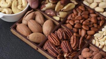 Box with various nuts cashew, macadamia, peanut, cedar, pecan, walnut, brazil, hazelnut on dark textured background video