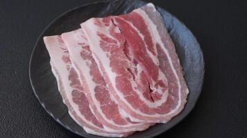 Fresh raw bacon sliced with spices and herbs on a dark concrete background video