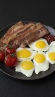 A hearty, delicious breakfast with fried eggs, bacon and tomatoes with salt, spices and herbs video