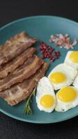 A hearty, delicious breakfast with fried eggs, bacon and tomatoes with salt, spices and herbs video
