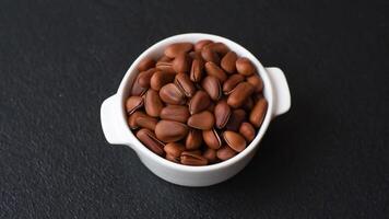 Delicious nutritious cedar nuts in ceramic bowl on dark concrete background video