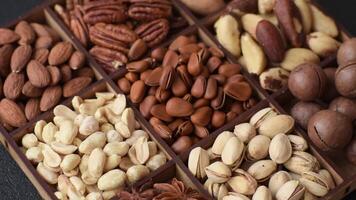 Box with various nuts cashew, macadamia, peanut, cedar, pecan, walnut, brazil, hazelnut on dark textured background video