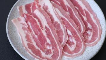 Fresh raw bacon sliced with spices and herbs on a dark concrete background video