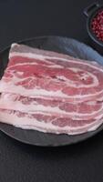 Fresh raw bacon sliced with spices and herbs on a dark concrete background video