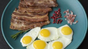 A hearty, delicious breakfast with fried eggs, bacon and tomatoes with salt, spices and herbs video