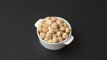 Delicious nutritious hazelnut in ceramic bowl on dark concrete background video