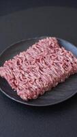 Fresh raw ground minced beef with salt and spices on textured concrete background video