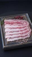 Fresh raw bacon sliced with spices and herbs on a dark concrete background video