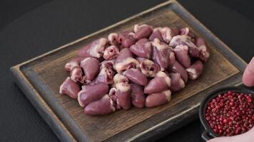 Raw chicken hearts with salt, spices and herbs on a dark concrete background video