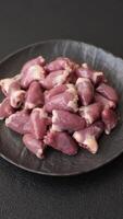 Raw chicken hearts with salt, spices and herbs on a dark concrete background video