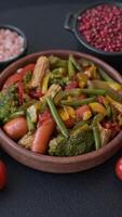 Mix of vegetables corn, carrots, peppers, broccoli, onions in teriyaki sauce on a ceramic plate on a dark concrete background video
