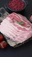 Fresh raw bacon sliced with spices and herbs on a dark concrete background video