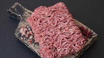 Fresh raw ground minced beef with salt and spices on textured concrete background video