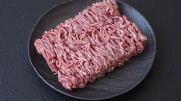 Fresh raw ground minced beef with salt and spices on textured concrete background video
