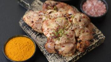 Grilled boneless chicken thigh with salt, spices and herbs on a dark concrete background video