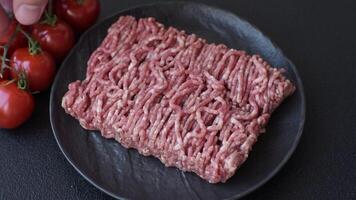 Fresh raw ground minced beef with salt and spices on textured concrete background video