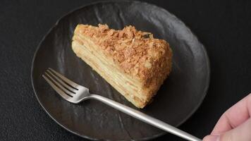 Piece of sweet layer cake Napoleon with custard on a dark concrete background video