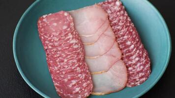 Delicious fresh smoked sausages cut with slices on a dark concrete background video