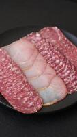 Delicious fresh smoked sausages cut with slices on a dark concrete background video