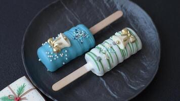 Natural popsicle ice cream on a stick covered with chocolate in the style and colors of Christmas and New Year on a dark concrete background video