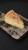 Piece of sweet layer cake Napoleon with custard on a dark concrete background video