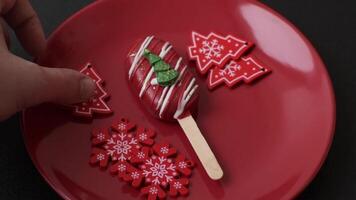 Natural popsicle ice cream on a stick covered with chocolate in the style and colors of Christmas and New Year on a dark concrete background video