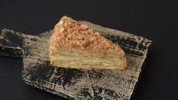 Piece of sweet layer cake Napoleon with custard on a dark concrete background video
