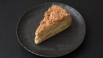 Piece of sweet layer cake Napoleon with custard on a dark concrete background video