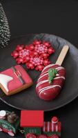 Natural popsicle ice cream on a stick covered with chocolate in the style and colors of Christmas and New Year on a dark concrete background video