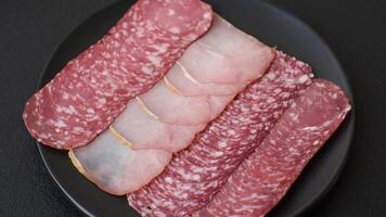 Delicious fresh smoked sausages cut with slices on a dark concrete background video
