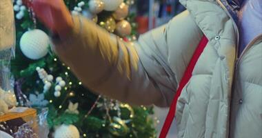 New Year tree with toys in a large supermarket. A woman walks past the tree and touches the toys on the tree video