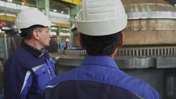 An Industrial Worker is attentively Observing the Machinery Process in a Busy Factory Setting. Stock Clip video