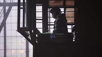 A silhouette of a worker in a dimly lit space highlights their effort amid tools and equipment. Stock Clip video