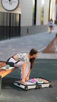 A girl joyfully exploring a myriad of colors showcased in a suitcase while sitting by a bench video