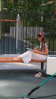 A young girl happily reading a book while sitting in a vibrant playground setting video
