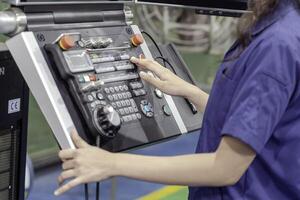 Closeup and crop hand of technician Engineer wearing uniform touch, press the button of automated machinery in industrial workshop. photo
