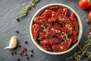 Sun-dried tomatoes packed in a bowl with herbs and spices on a kitchen countertop ready for use in culinary photo