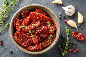 Sun-dried tomatoes packed in a bowl with herbs and spices on a kitchen countertop ready for use in culinary photo