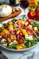 Colorful salad with fresh vegetables, prosciutto, mozzarella, and a glass of red wine served on a marble table photo