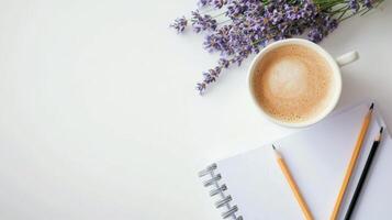Scented lavender in a small pot beside a cup of coffee and a notepad on a clean white table in a cozy workspace photo