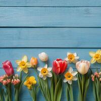 Colorful spring flowers arranged on a blue wooden surface showcasing various blooms with vibrant petals and photo