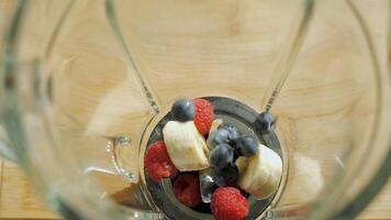 Adding raspberries, blueberries and bananas to a blender to make a smoothie. The smoothie ingredients are ready to be blended. video