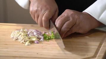 Cutting Bird s eye chilli and combine mix with lemon grass, garlic, shallot on a wooden cutting board into slice pieces with a kitchen knife by professional chef. video