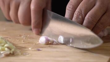 Slicing Shallot, red onion on a wooden cutting board into slice pieces with a kitchen knife by professional chef. video