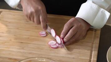 Slicing Radis on a wooden cutting board into slice pieces with a kitchen knife by professional chef. video