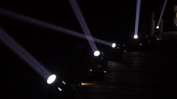 Spotlight machines create light beams with moving its direction in the dark night on walking wood way video